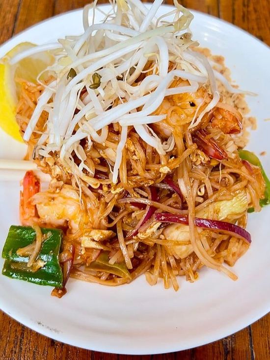 Plato de pad thai con brotes de soja, gambas y lima